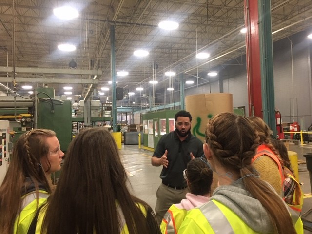 man speaking to students wearing safety vests